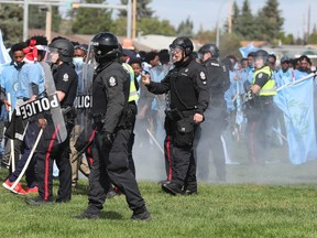 Police try and control a riot that broke out between riot between anti-Eritrean government protesters (pictured in blue) and pro-government Eritrean supporters at the Rosslyn Park soccer fields, 113A Street and 132 Avenue, on Saturday, Aug. 19, 2023.
