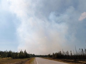 Smoke billows on the road beside the highway near the town of Enterprise, Northwest Territories, on August 20, 2023. Enterprise and Hay River were put on evacuation orders prior to the city of Yellowknife. The town of Enterprise, Northwest Territories, was burned to the ground by forest fires.