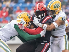 Calgary Stampeders running back Ka’Deem Carey gets tackled by Edmonton Elks defensvie backs Ed Gainey, left, and Mark McLaurin during the Labour Day Classic at McMahon Stadium on Monday, Sept. 4, 2023.