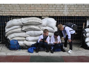 Ukrainian schoolchildren sit next to sand bags in the school yard after a First Bell ceremony, marking the beginning of the school year in the western Ukrainian city of Lviv on September 1, 2023.