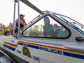 An RCMP officer looks on as children explore an RCMP boat on display