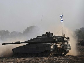 An Israeli Merkava tank is deployed with other armoured vehicles along Israel's border with Gaza on Oct. 24, 2023. (Photo by Aris MESSINIS / AFP)