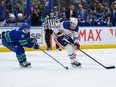 Leon Draisaitl (29) of the Edmonton Oilers is pursued by Nils Hoglander (21) of the Vancouver Canucks at Rogers Arena on Wednesday, Oct. 11, 2023, in Vancouver.
