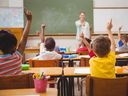 Pupils raise their hands during class in an elementary school
stock photo.