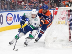 Vancouver Canucks' Quinn Hughes (43) and Edmonton Oilers' Evander Kane (91) battle for the puck during third period NHL action in Edmonton on Saturday, Oct. 14, 2023.