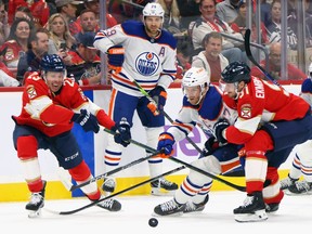 Carter Verhaeghe #23 and Aaron Ekblad #5 of the Florida Panthers defend against Connor McDavid #97 of the Edmonton Oilers during the first period at Amerant Bank Arena on Monday, Nov. 20, 2023, in Sunrise, Florida.