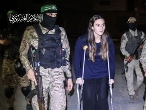 An image grab from a handout video released by the Hamas Media Office shows Hamas fighters accompanying a newly released Israeli hostage Maya Regev to a Red Cross vehicle, in the Gaza Strip early on Nov. 26, 2023.