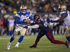 Winnipeg Blue Bombers quarterback Zach Collaros (8) looks to throw as he evades a tackle from Montreal Alouettes defensive lineman Lwal Uguak (96) during the first half of football action at the 110th CFL Grey Cup in Hamilton, Ont., on Sunday, November 19, 2023.