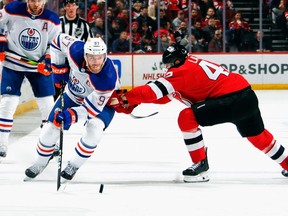 NEWARK, NEW JERSEY - DECEMBER 21: Connor McDavid #97 of the Edmonton Oilers moves past Curtis Lazar #42 of the New Jersey Devils during the first period at Prudential Center on December 21, 2023 in Newark, New Jersey.