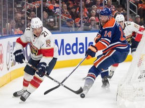 Florida Panthers' Nick Cousins (21) and Edmonton Oilers' Mattias Ekholm (14) battle for the puck