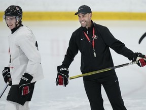 Canada's head coach Alan Letang, right, laughs with forward Fraser Minten at practice during Canadian world junior selection camp in Oakville, Ont., on Monday, Dec. 11, 2023.