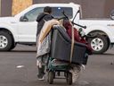 A person moves their belonging to another location during an encampment eviction near the Herb Jamieson Centre shelter on Saturday, Dec. 30, 2023, in Edmonton.