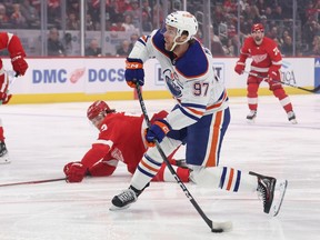 Connor McDavid prepares to shoot, a Detroit player lies on the ice in the background