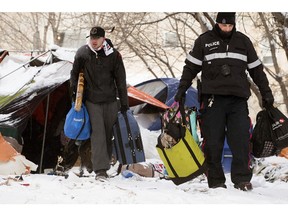 Arlen Plashka is escorted out of his tent at a homeless encampment being removed near 95 Street and 101A Avenue in Edmonton on Wednesday, Jan. 10, 2024. Plashka had been living at the encampment for three months.