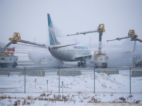 A WestJet Boeing 737 is deiced at the Calgary International Airport on Tuesday, December 20, 2022. A recent bout of extreme cold weather rendered deicing fluid ineffective, the airline said. That and other effects of low temperatures led to the cancellation of hundreds of flights.