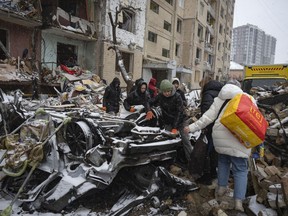 Volunteers and residents clear debris of an apartment building destroyed after Russian attack in Kyiv, Ukraine, Wednesday, Jan. 3, 2024.