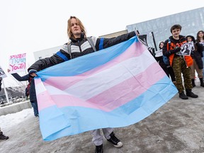 A student of Joane Cardinal-Schubert High School holds out a Trans Pride flag during a walkout on Wednesday, February 7, 2024 to protest the UCP government’s recently announced policies around transgender youth.
