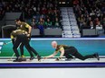 Manitoba-Carruthers skip Brad Jacobs, right, delivers a rock as second Derek Samagalski, back left, and lead Connor Njegovan, front left, sweep.