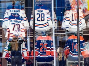 Staff at the official Oilers store rearrange jerseys displayed in the window on Saturday, April 20, 2024, as the team and fans prepare for round one of NHL playoffs that begin Monday.