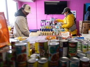 Volunteers Gabriel Balicanta, left, and Sharon Nolasco help load hampers for the Forest Lawn Community Food Bank in Calgary on Tuesday, April 16, 2024.