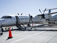 A passenger boards a WestJet Encore Bombardier Q400 twin-engined turboprop aircraft in Kamloops, B.C., in 2023.