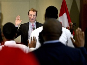 New Canadians raise their right hands as Minister of Immigration, Refugees and Citizenship Marc Miller administers the Oath of Citizenship during a citizenship ceremony in Ottawa, on Wednesday, Feb. 28, 2024.