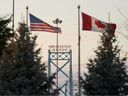 Canadian and American flags fly on the Canadian side of the Ambassador Bridge in Windsor, Ont., on March 8, 2025.