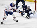 Connor McDavid of the Edmonton Oilers (97) passed Winnipeg Jets goalkeeper Eric Comre (1) during the first phase of the NHL action in Winnipeg Sunday, April 13, 2025.