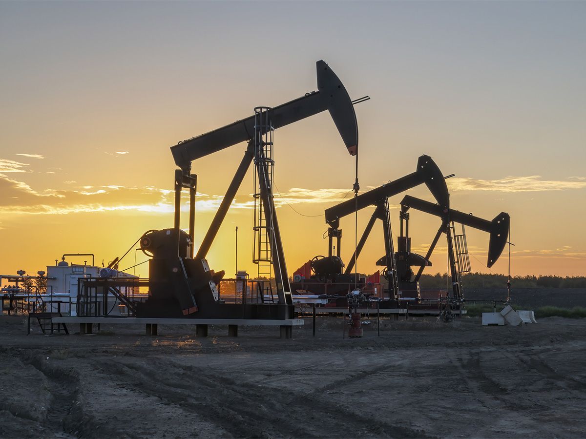 Three oil well pumpjacks at sunrise near Crossfield, Alberta.