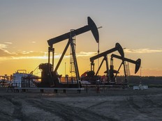 Three oil well pumpjacks at sunrise near Crossfield, Alberta.