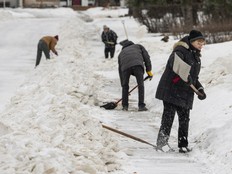 Residents clear chunks of snow and ice created after a grader cleared the street in font of their homes into a windrow on Tuesday, January 20, 2026 in Edmonton.