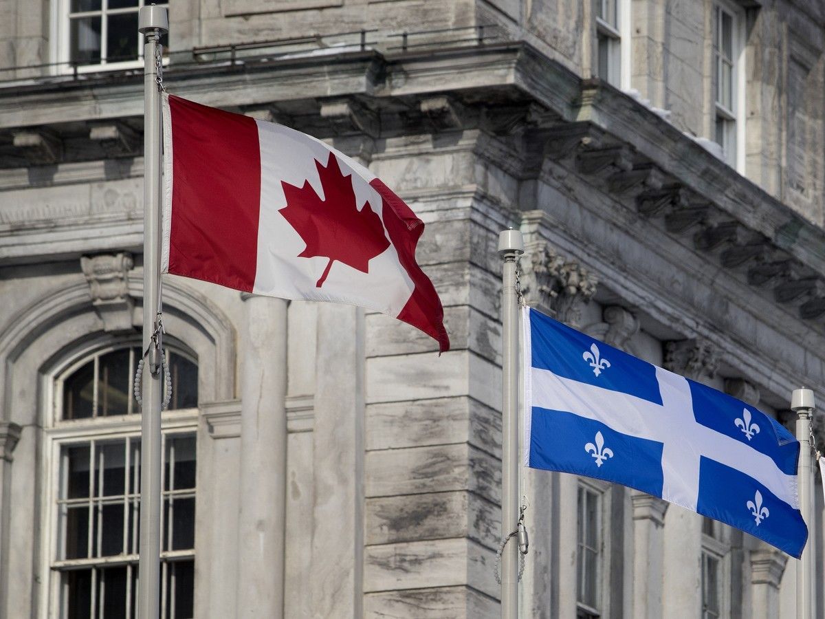 The Canadian flag has been moved from its place on the centre flag pole to the far left to make room for the Quebec flag on the centre pole, as seen at city hall in Montreal in 2018. Allen McInnis / MONTREAL GAZETTE