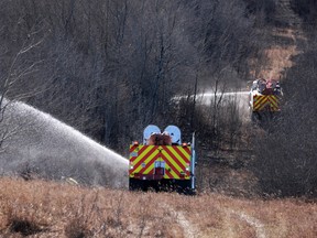Canadian Forces fire trucks extinguish hot spots on the edge of Canadian Forces Base Wainwright on Sunday, October 18, 2026. The blaze spread after killing several soldiers and injured dozens more on Saturday afternoon.
