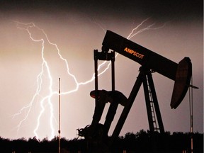 Lightning strikes in the distance as an oil pump-jack sits idle west of Edmonton, Alta.