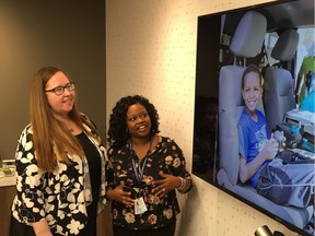 Alberta Labour Minister Christina Gray, left, is shown photos of clients who have benefited from Catholic Social Services Immigration and Settlement Services programs by Ese Ejebe of Catholic Social Services on Oct. 20, 2017 in Edmonton.