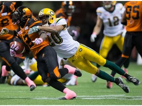 Edmonton Eskimos' Johnny Adams, right, dives to tackle B.C. Lions' Chris Rainey during the first half of a CFL football game in Vancouver, B.C., on Saturday October 21, 2017.