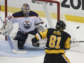 Pittsburgh Penguins winger Phil Kessel tries to swat the puck out of the air in front of Edmonton Oilers goalie Cam Talbot during NHL action in Pittsburgh on Oct. 24, 2017.