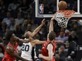 Manu Ginobili of the San Antonio Spurs banks a shot off the glass for two points during NBA action against the Toronto Raptors Monday at the ACC. Defending for Toronto are Devon Wright, left, and Jakob Poeltl. The Spurs handed the Raptors their first loss of the season, 101-97.