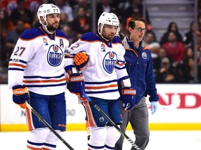 Andrej Sekera of the Edmonton Oilers is helped off the ice by Milan Lucic and a trainer against the Anaheim Ducks on May 5, 2017, during Game 5 of their NHL playoff series.