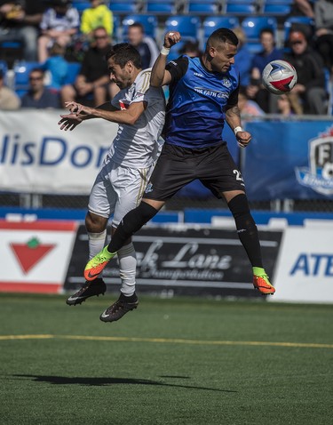 Shawn Nicklaw of the FC Edmonton, heads the ball away from Austin Da Luz of North Carolina FC at Clark Stadium on September 10, 2017.  Photo by Shaughn Butts / Postmedia