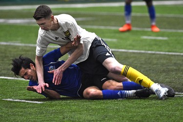 University of Alberta Golden Bears Easton Ongaro (19) falls on FC Edmonton Mauro Eustaquio (blue) during an exhibition game between the two teams at Foote Field in Edmonton, Tuesday, March 7, 2017. Ed Kaiser/Postmedia