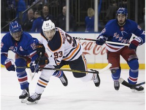 New York Rangers defenseman Marc Staal, left, and center Mika Zibanejad, right, chase down Edmonton Oilers center Ryan Nugent-Hopkins during the first period of an NHL hockey game, Saturday, Nov. 11, 2017, in New York.
