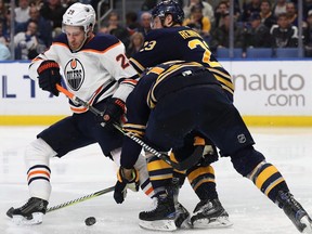 Jake McCabe #19 and Sam Reinhart #23 of the Buffalo Sabres check Leon Draisaitl #29 of the Edmonton Oilers off the puck during the third period at the KeyBank Center on November 24, 2017 in Buffalo, New York.