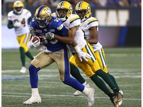 Winnipeg Blue Bombers running back Andrew Harris drags a pair of Edmonton Eskimos tacklers during CFL action in Winnipeg on Thurs., Aug. 17, 2017.