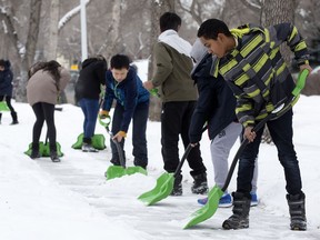 Students from John A. McDougall School shovel in their neighbourhood in February. The city is urging residents to shovel their sidewalks, yet doesn't ensure its own walks are free of snow and ice.