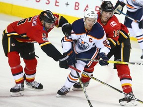 Edmonton Oilers centre Connor McDavid, middle, splits Calgary Flames defenceman Mark Giordano, left, and forward Matthew Tkachuk during NHL action in Calgary on Dec. 2, 2017.