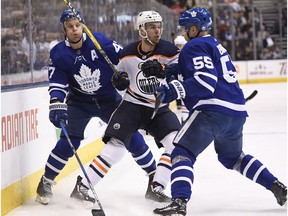 Toronto Maple Leafs defenceman Andreas Borgman (55) and centre Leo Komarov (47) check Edmonton Oilers centre Connor McDavid in Toronto on Sunday, Dec. 10, 2017.