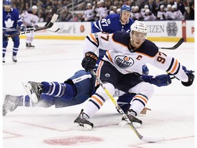 Edmonton Oilers centre Connor McDavid (97) drives to the net past sprawling Toronto Maple Leafs defenceman Ron Hainsey in Toronto on Sunday, Dec. 10, 2017.