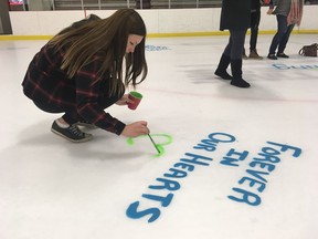 Community members paint messages on the ice at the Whitecourt Twin Arenas to honour slain brothers Ryder and Radek MacDougall before a memorial hockey game on Dec. 16, 2017.