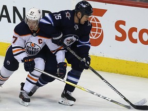 Winnipeg Jets centre Matt Hendricks (right) keeps Edmonton Oilers centre Connor McDavid at bay in Winnipeg on Wed., Dec. 27, 2017.